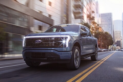 A blue Ford F-150® Lightning® being driven in the city