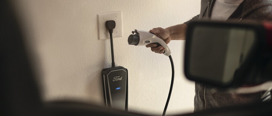 A man preparing to use a Ford Mobile Power Cord plugged into a wall