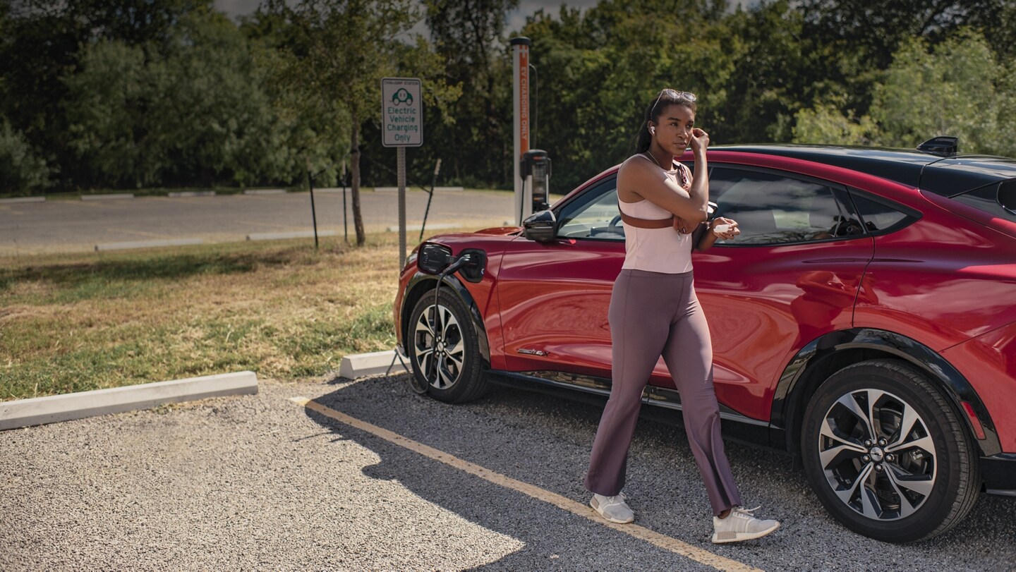 A woman parks her 2023 Ford Mustang Mach-E at a public charging station