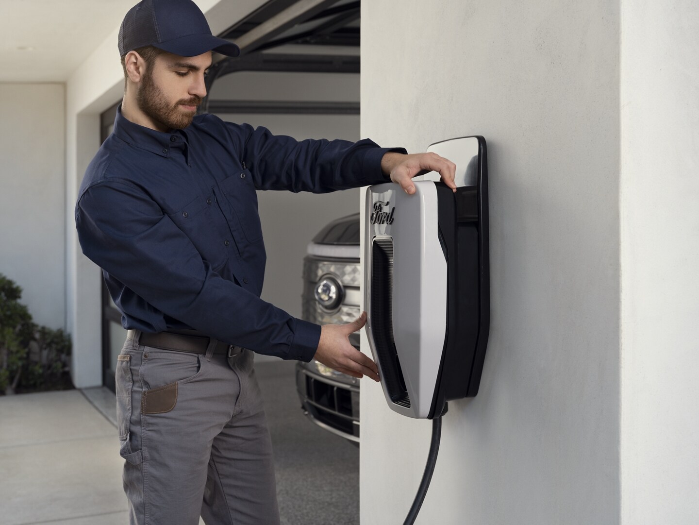 An installer mounting a Ford Charge Station Pro to a wall