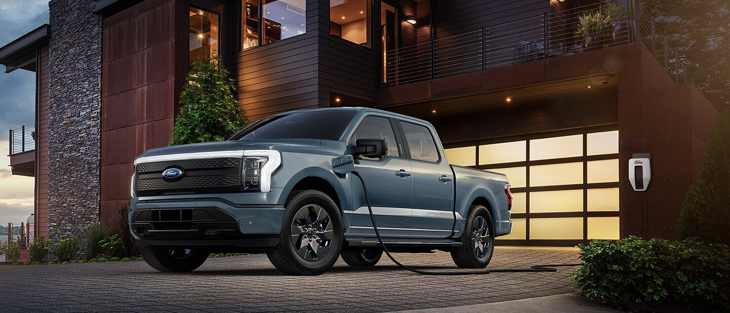 An F-150® Lightning® truck charging outside of a garage