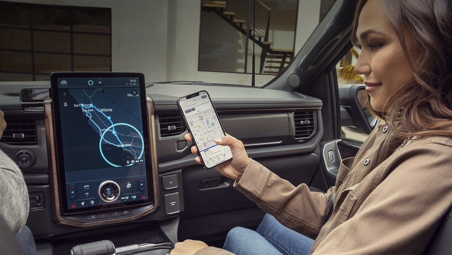 A woman uses the FordPass™ Power My Trip feature on her smartphone