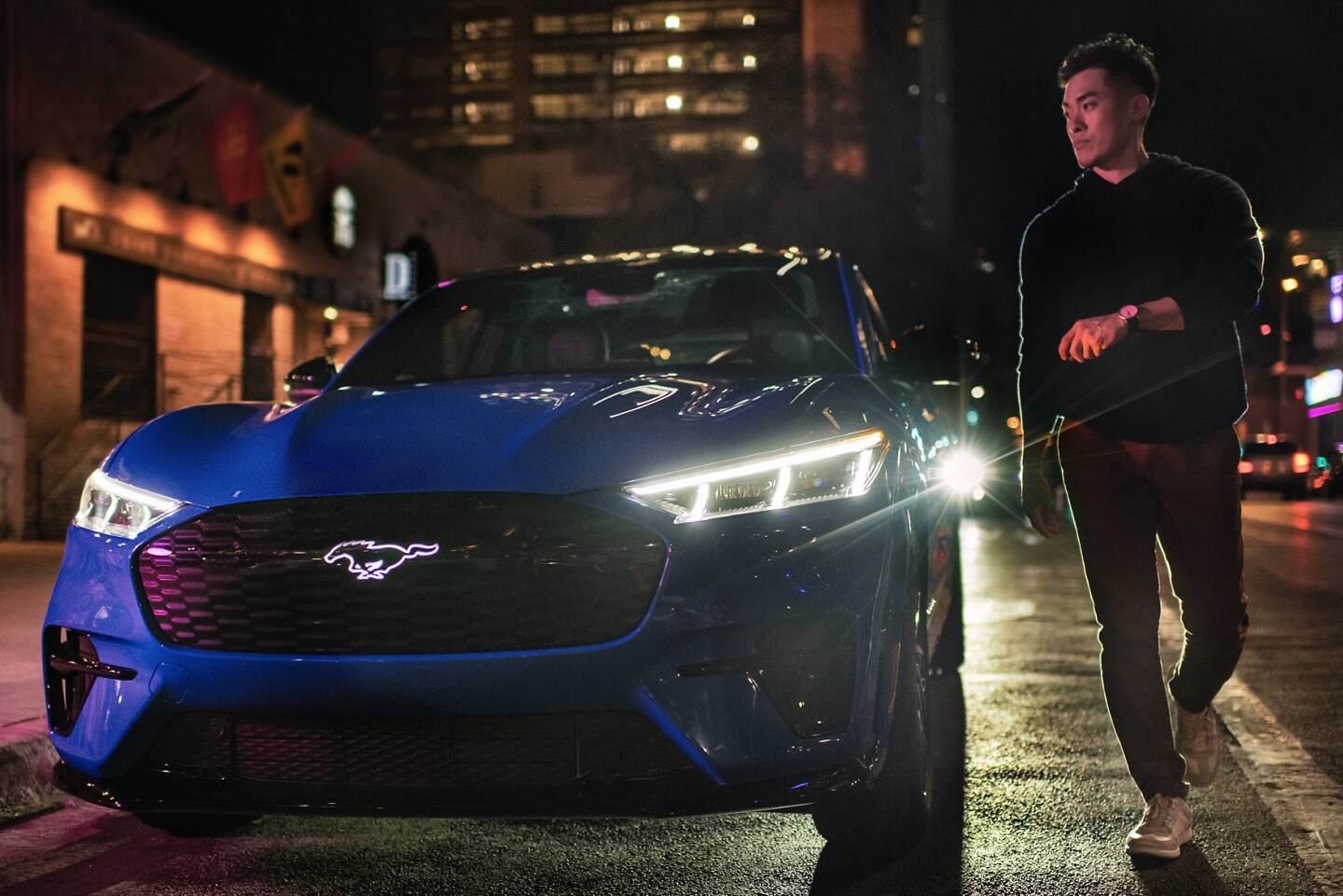 A man exits a 2023 Ford Mustang Mach-E® parked on a nighttime city street