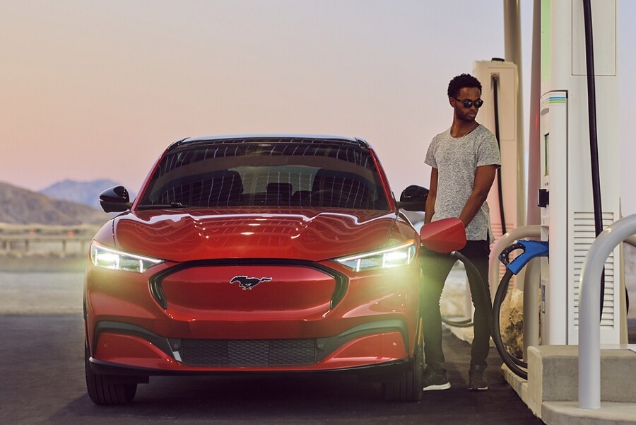 A man charges his 2023 Ford Mustang Mach-E® at a BlueOval™ charging station