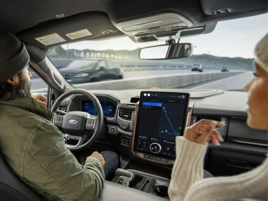 A driver and passenger in a Ford Driver's hands are off the wheel while they use BlueCruise Hands-Free Highway technology