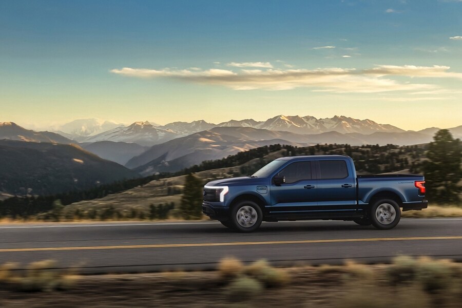 2025 Ford F-150® Lightning® driving down road with mountains in background
