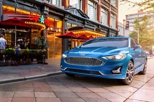 A 2020 Ford Fusion in velocity blue parked next to a restaurant