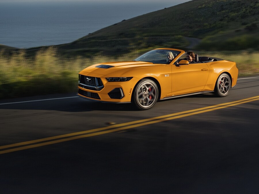 A 2026 Ford Mustang® GT Premium Convertible model being driven on a seaside highway