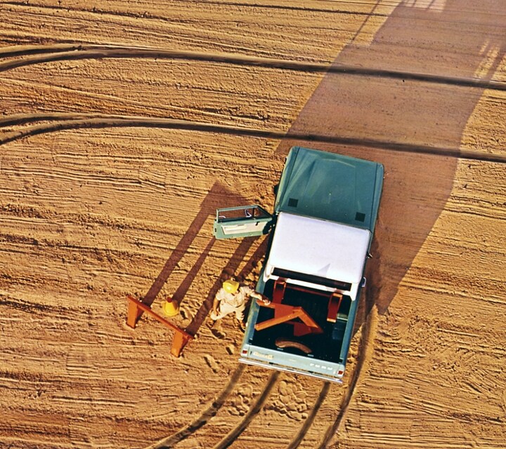 A man unloading wood from the back of a 1969 Ford Bronco Pickup in Lunar Green