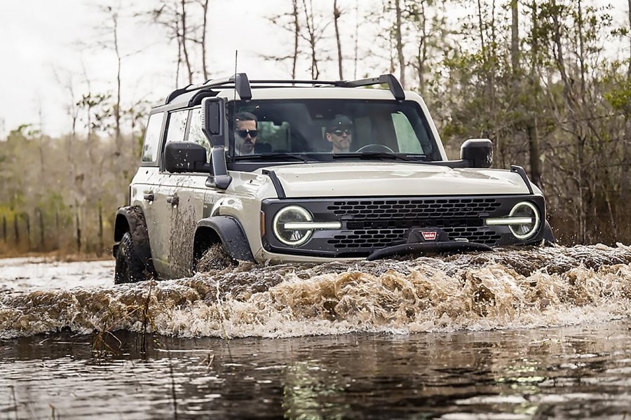 Four-door 2022 Ford Bronco® Everglades™ in Desert Sand being driven through water