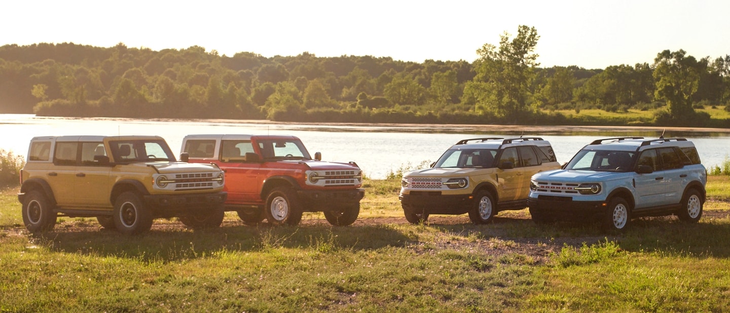 Two 2023 Bronco® and two Bronco® Sport models parked in a clearing. One Heritage and one Heritage Limited per model