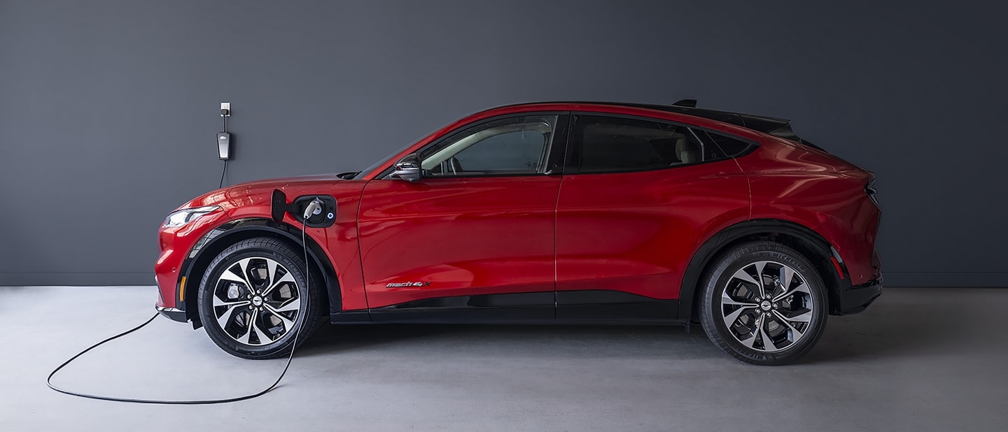 Rapid Red 2022 Ford Mustang Mach-E plugged into a Ford Mobile Charger in a garage