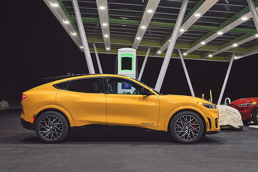 Cyber Orange 2022 Ford Mustang Mach-E parked at a roadside charging station