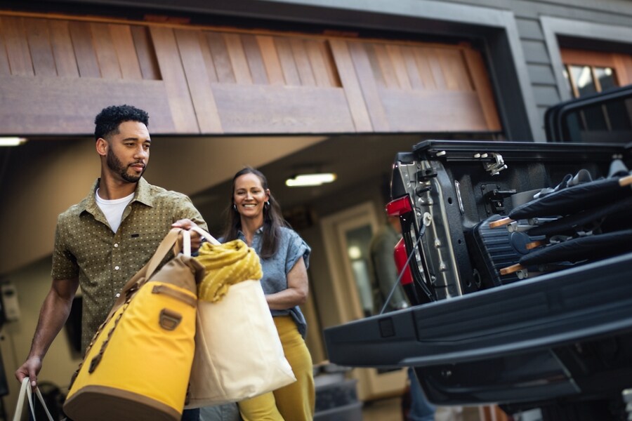 A man and a woman load bags into the back of a Ford F-150 Lightning truck. 