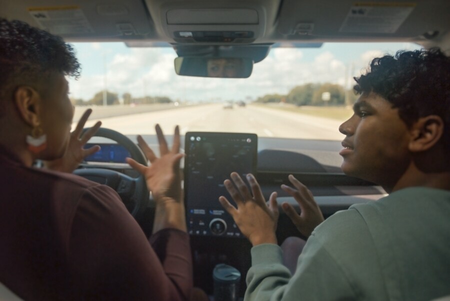 A woman and a teenager communicate in sign language while Ford BlueCruise is activated on a Ford Mustang Mach-E SUV. 