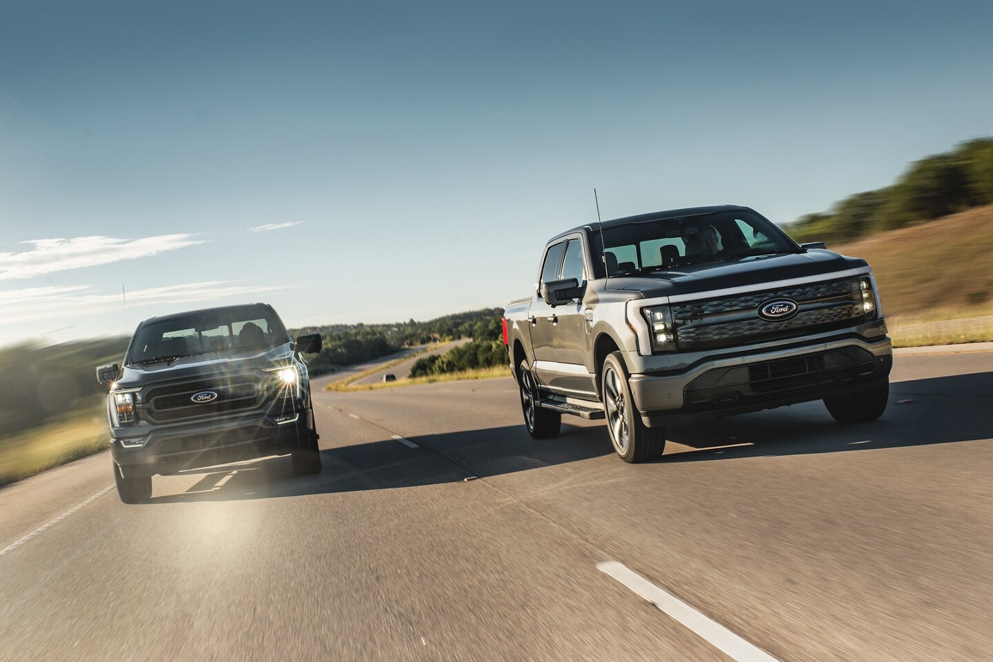 A Gray 2024 Ford F-150 and Lightning driving down two lane highway in the city outskirts