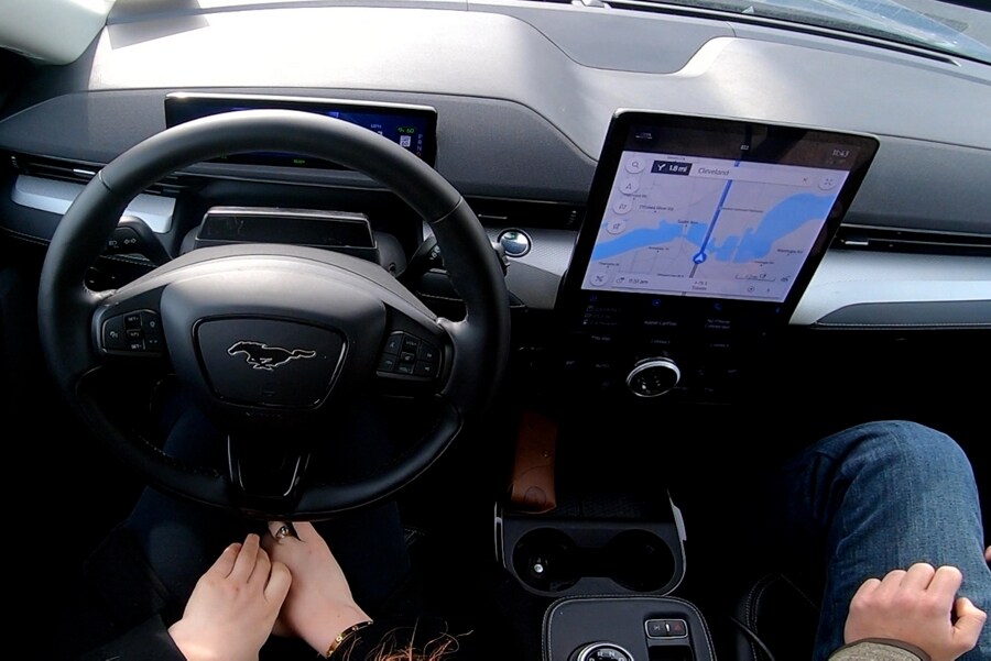 The driver in a Ford Mustang Mach-E SUV has their hands off the wheel while Ford BlueCruise is active.  