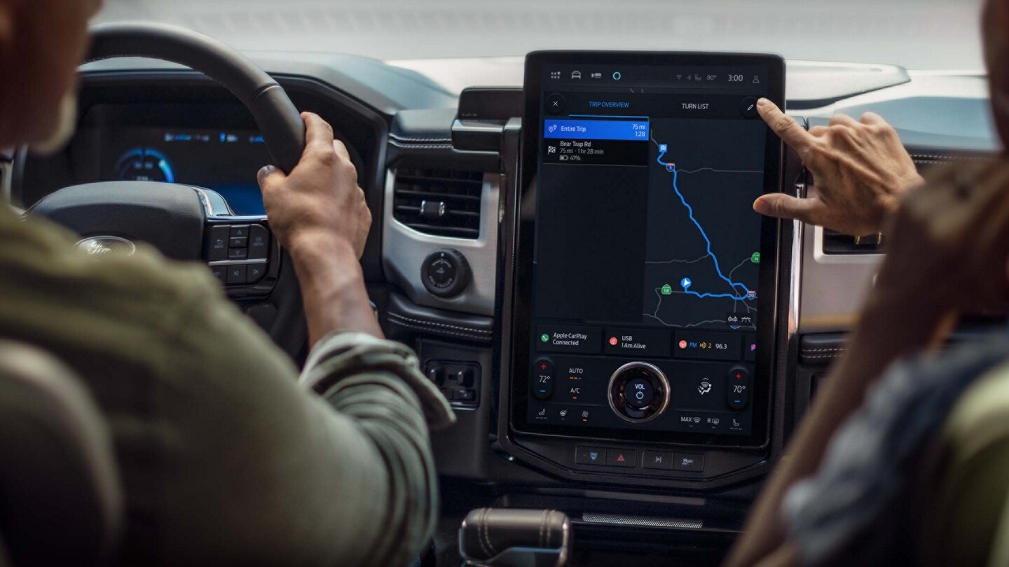 A driver and a passenger using Connected Navigation while driving in a Ford vehicle.