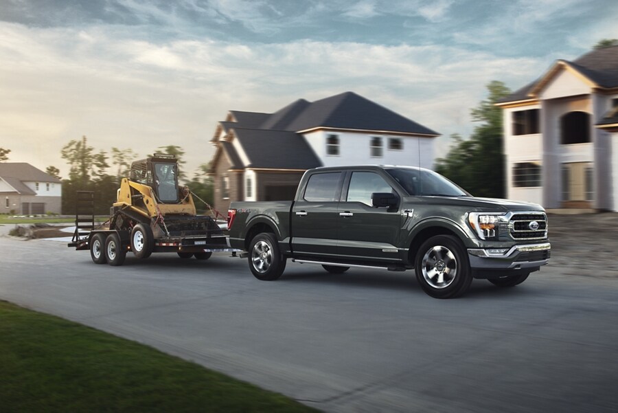 Ford F-150® 2022 tirando de un tractor por una calle suburbana