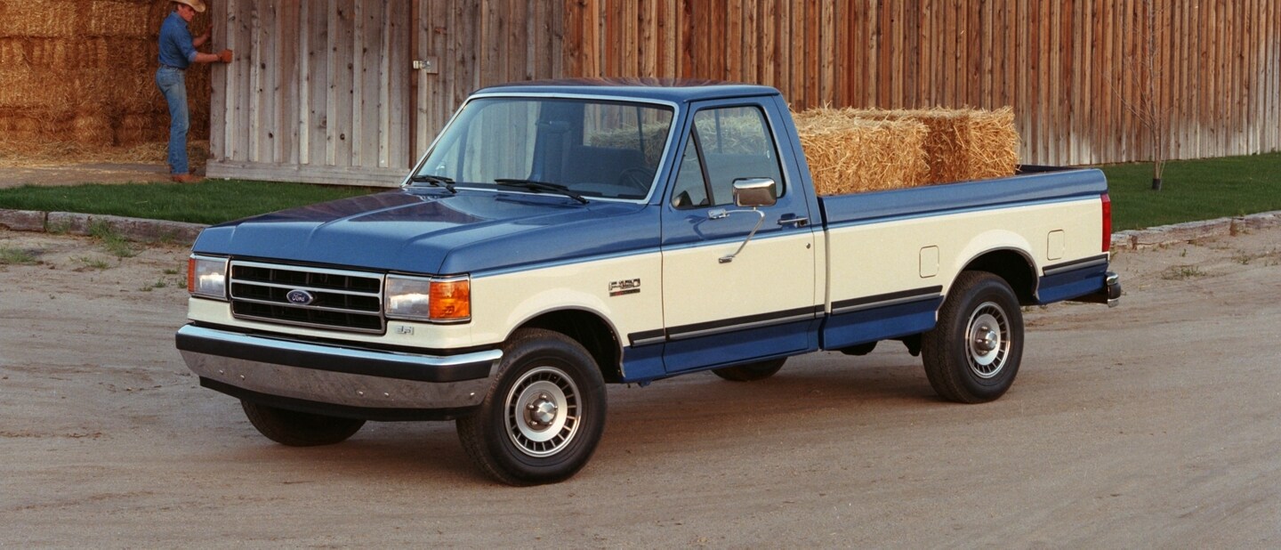 Vintage Ford F-150® truck parked near a barn with hay bales in the truck bed