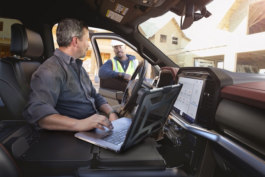 A man working on a laptop computer inside the cab of a 2022 Ford F-150®