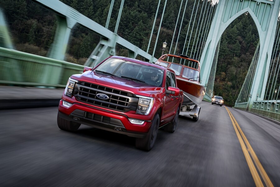 2023 Ford F-150® PowerBoost™ Hybrid in Race Red pulling a boat on an expansion bridge