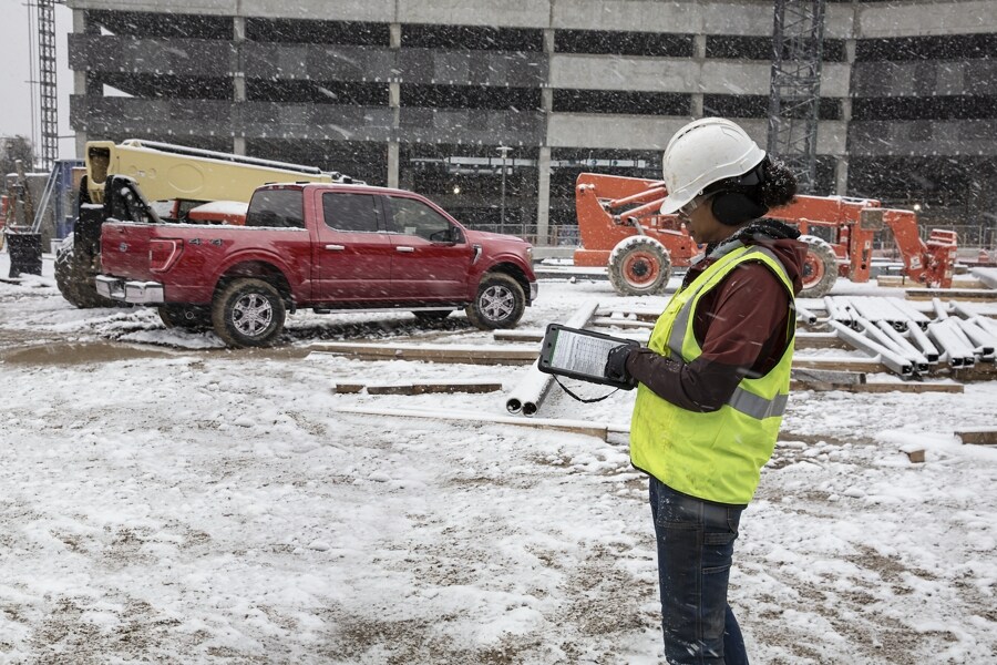 Female contractor at a snowcovered worksite with an 2022 Ford F-150® in Rapid Red in the background