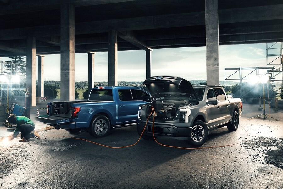Ford F-150® Lightning™ and F-150 LARIAT Crew Cab on a job site with a man using the F-150 Lightning to power his welder