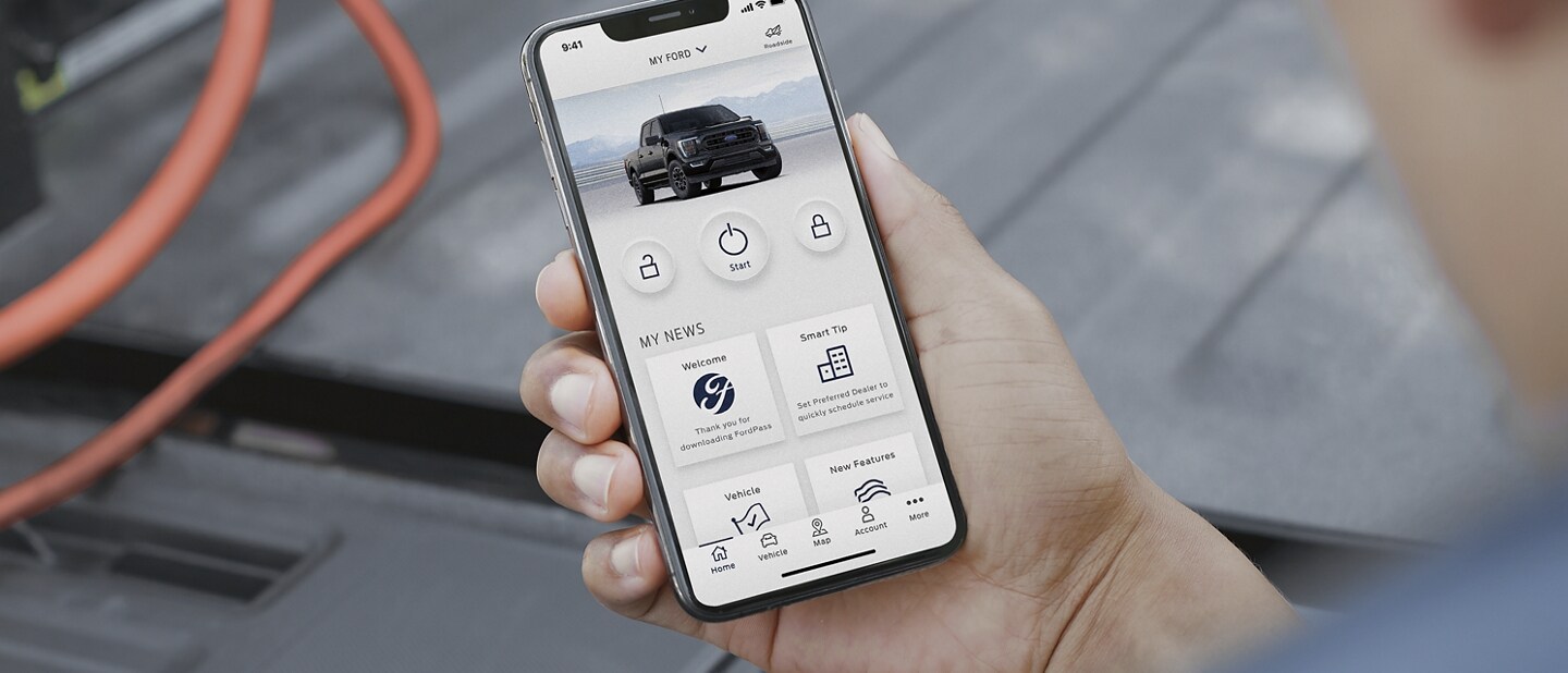 Close up of man holding a smartphone showing the Ford Pass app on screen