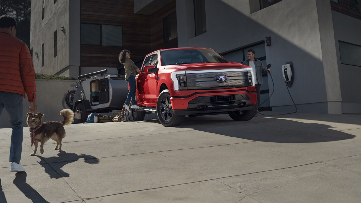 A couple prepares to leave home in their 2023 Ford F-150 Lightning® as the driver unplugs it from a charger