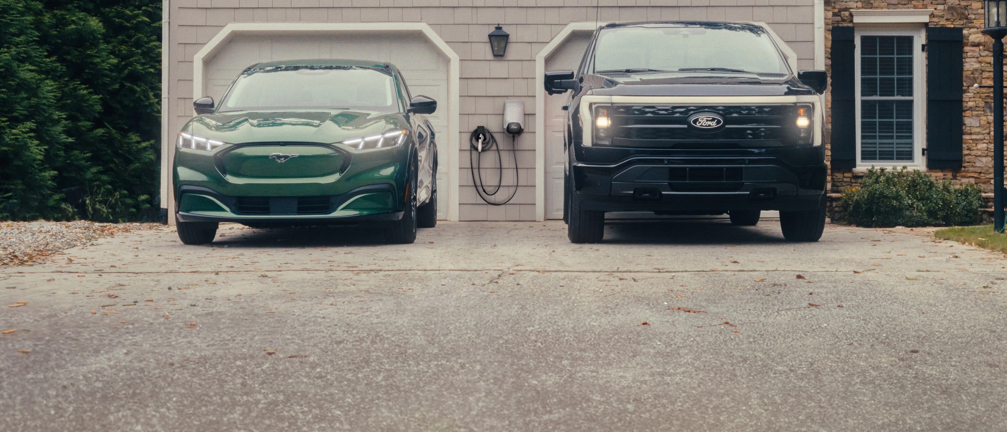 A Ford Mustang Mach-E and a Ford F-150 Lightning parked in a driveway