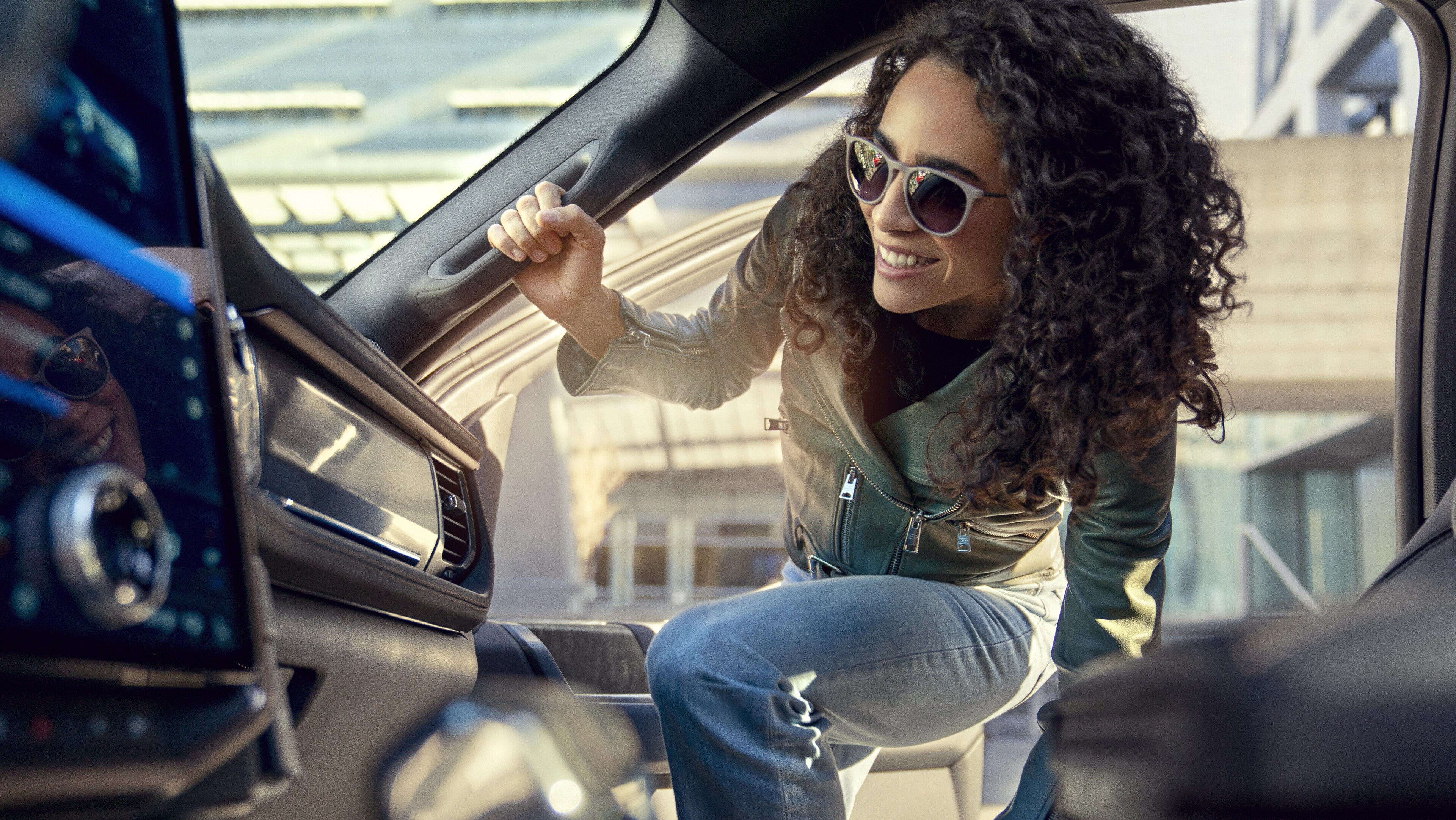 A young adult smiles while climbing into the passenger side of a new Ford vehicle
