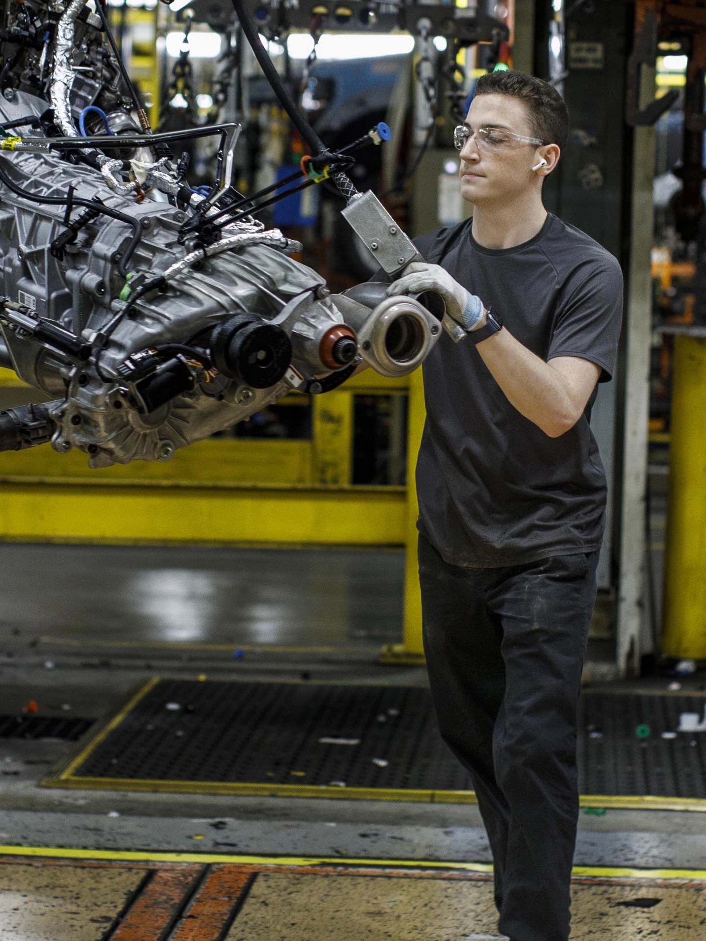 A person handling an engine inside an assembly plant