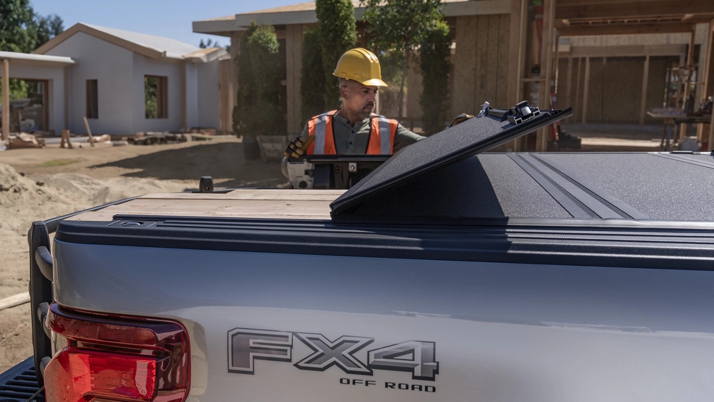 Construction worker opens the folding bed cover on a 2025 Ford F-150 Lightning®