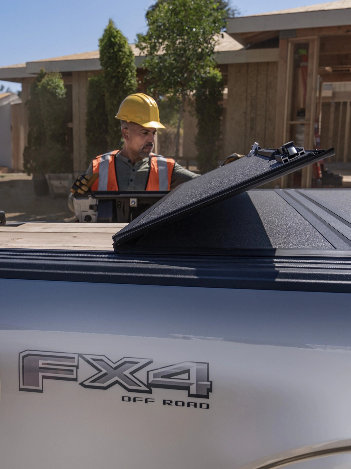 Construction worker opens the folding bed cover on an 2025 Ford F-150 Lightning®