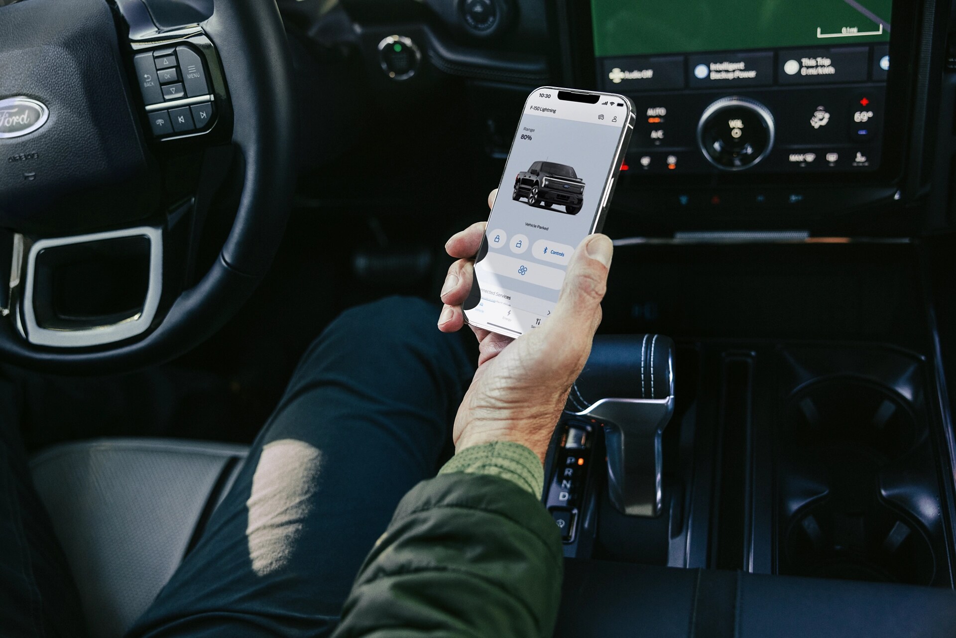 Person holding a phone displaying the FordPass® app inside a Ford electric vehicle