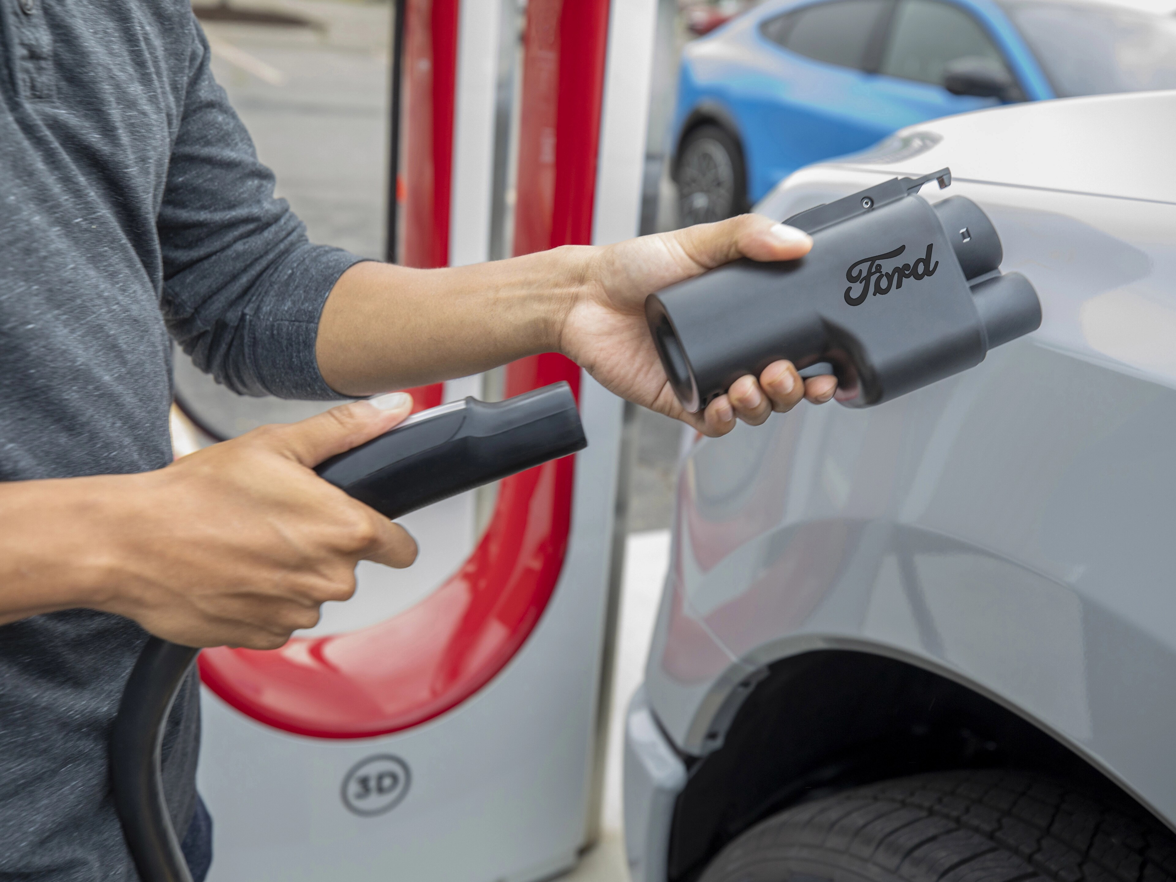 Person holding a NACS adapter for charging their Ford electric vehicle