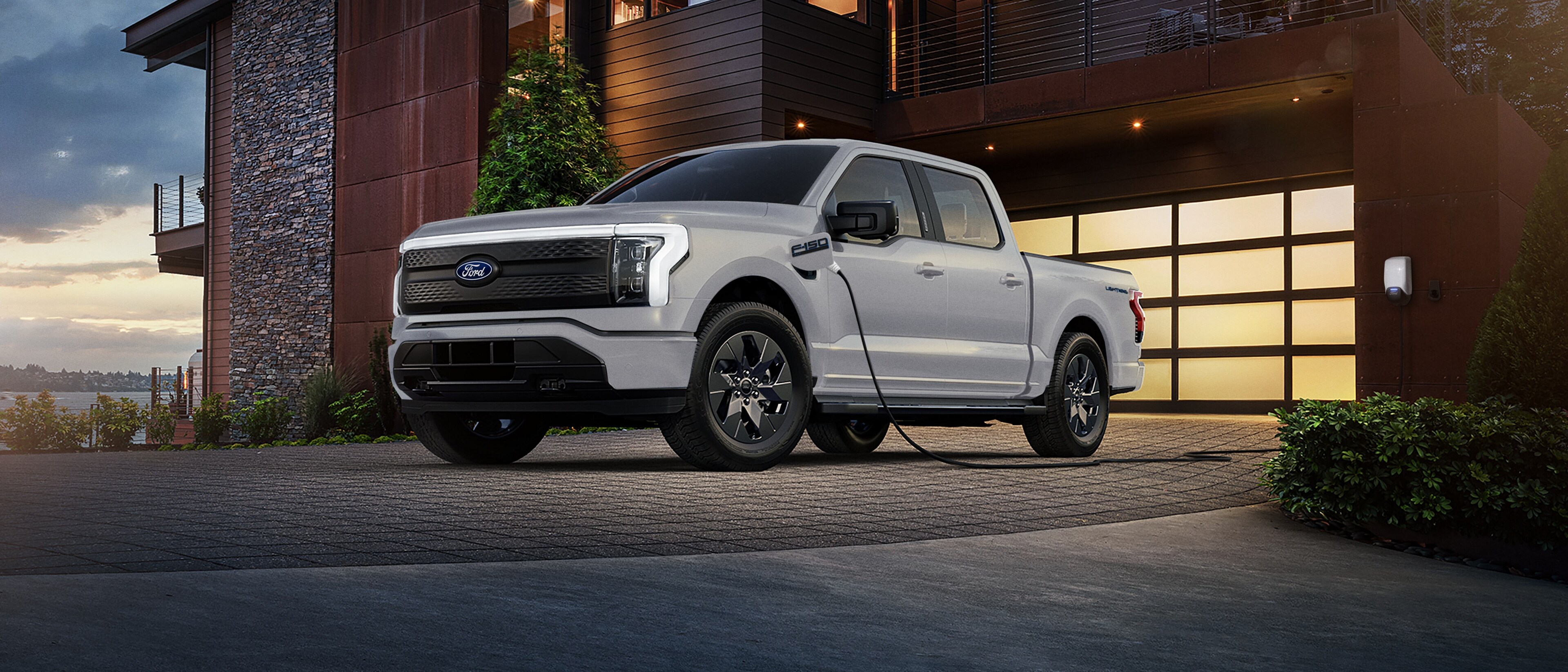 Ford F-150® Lightning® truck charging in the driveway of a modern luxury home