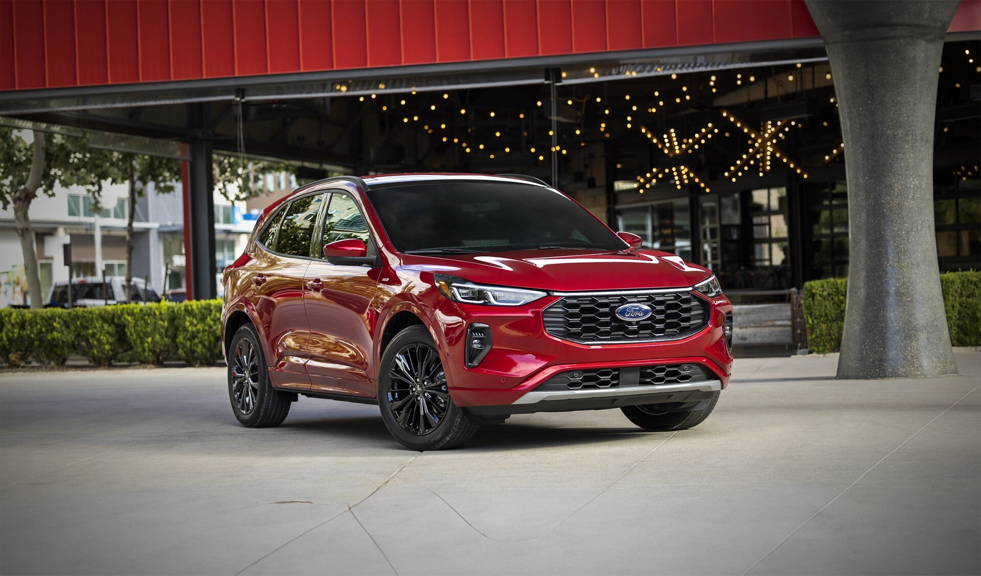 Red 2024 Ford Escape® SUV parked in front of a building with string lights