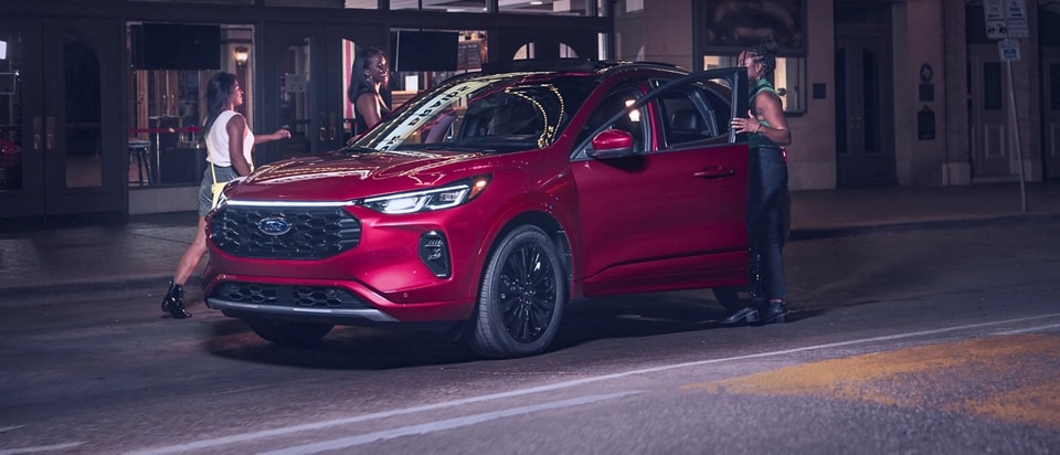 A group of friends get into a red 2025 Ford Escape® SUV at night