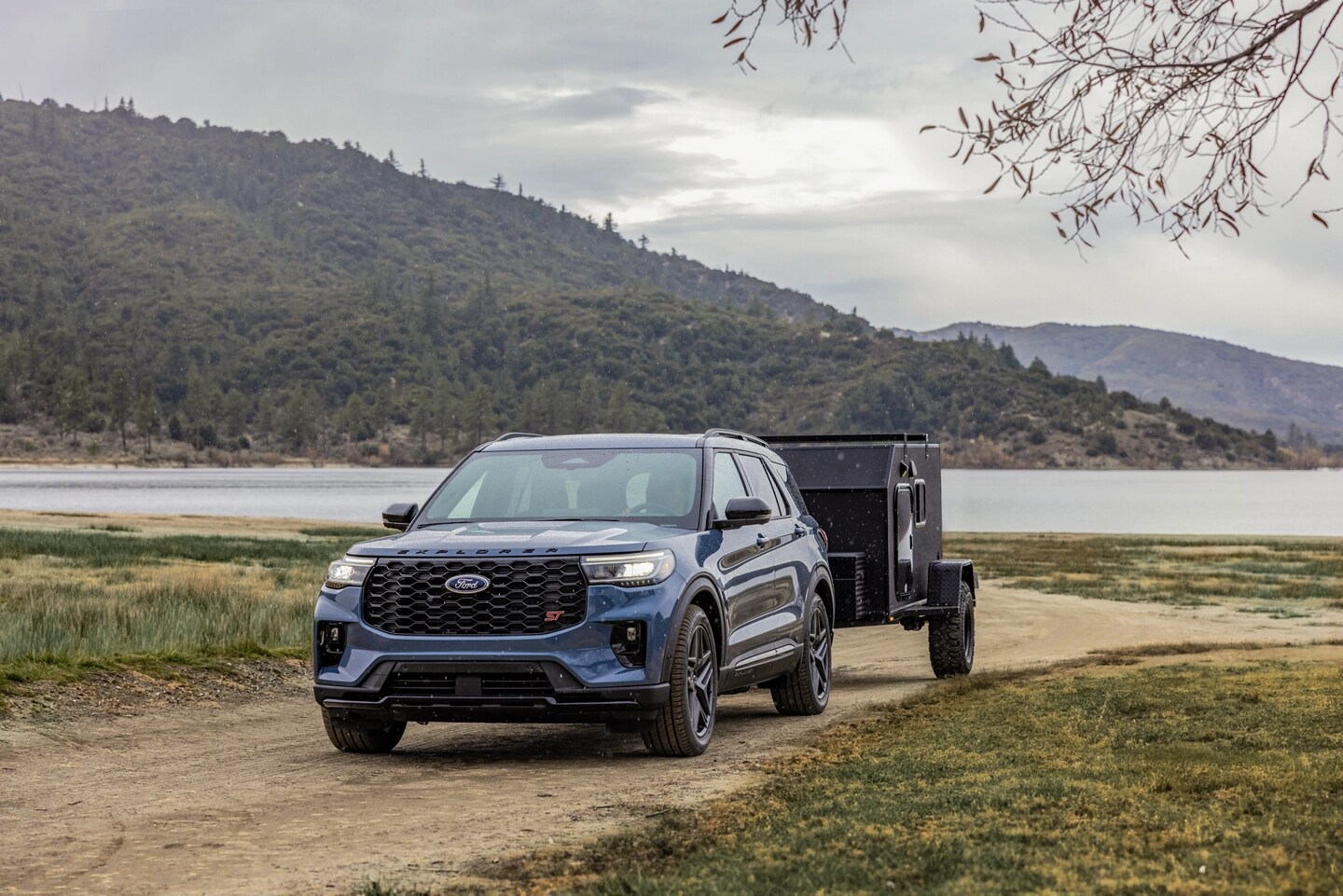 2025 Ford Explorer in blue towing a small black camper