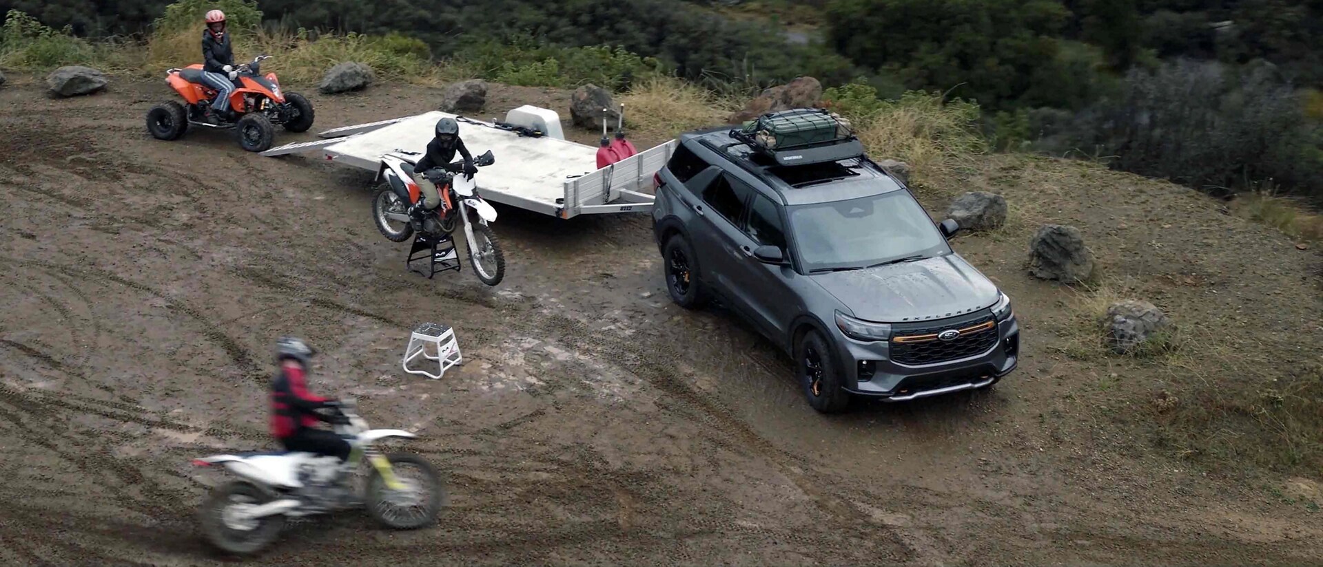 People using dirt bikes and an ATV near a 2026 Ford Explorer® Tremor® SUV