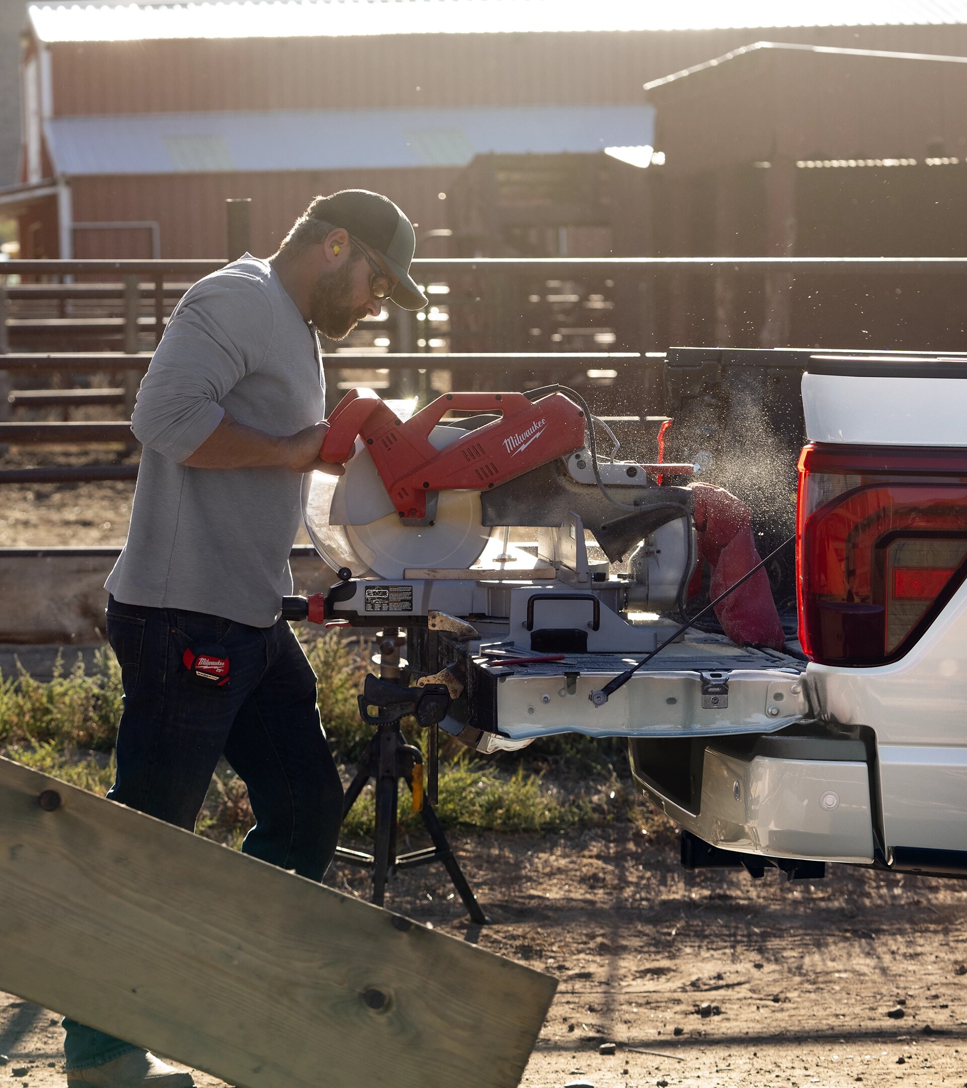 Man using a chop saw plugged into the Pro power Onboard™ feature on the tailgate of a 2026 Ford F-150® truck