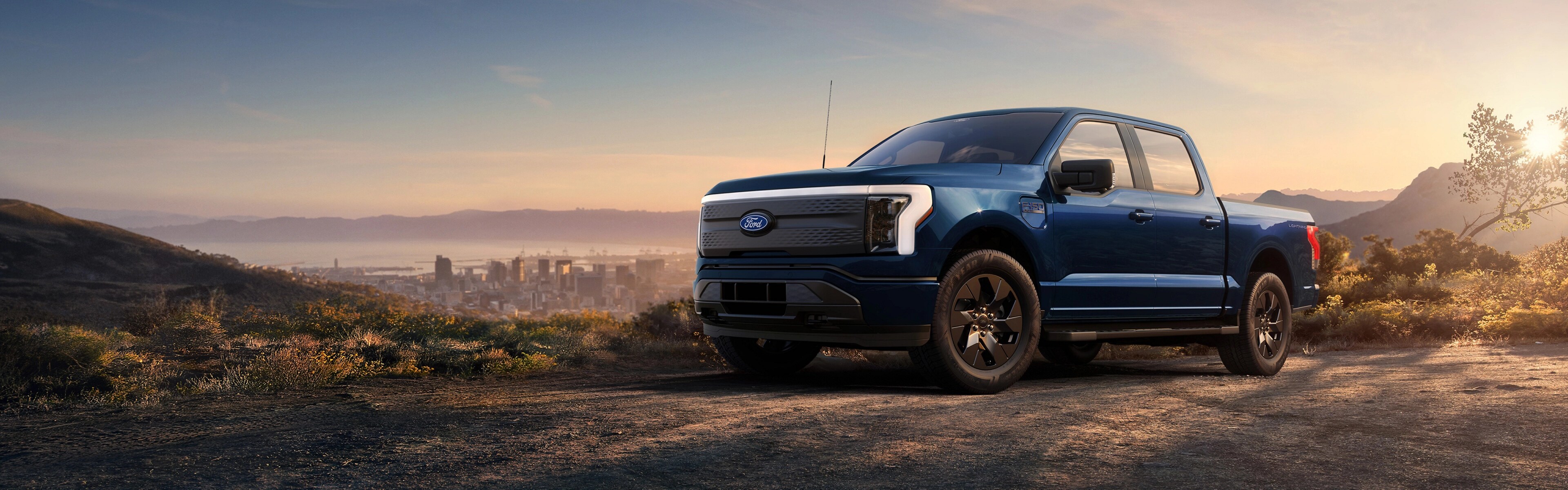 A 2025 Ford F-150® Lightning® pickup parked on a hilltop overlooking the Long Beach, California skyline