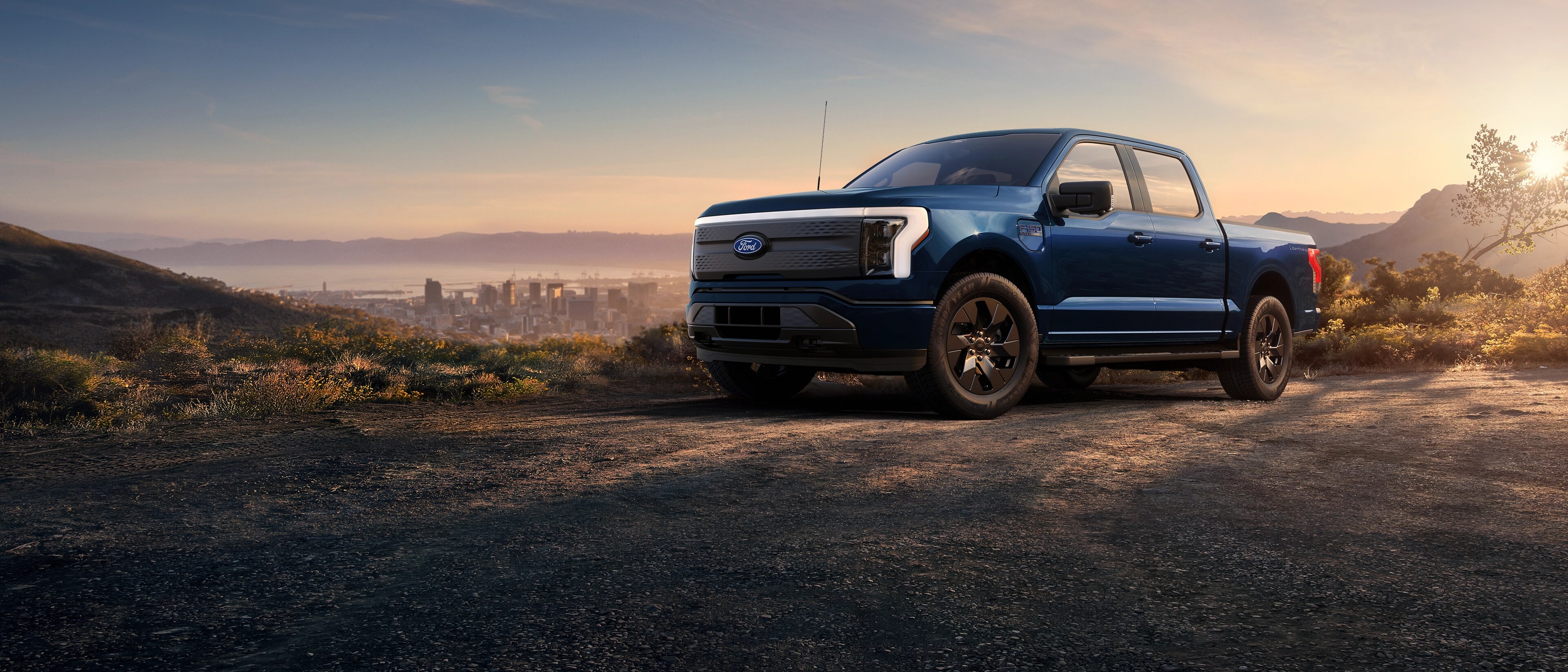 A 2025 Ford F-150® Lightning® pickup parked on a hilltop overlooking the Long Beach, California skyline