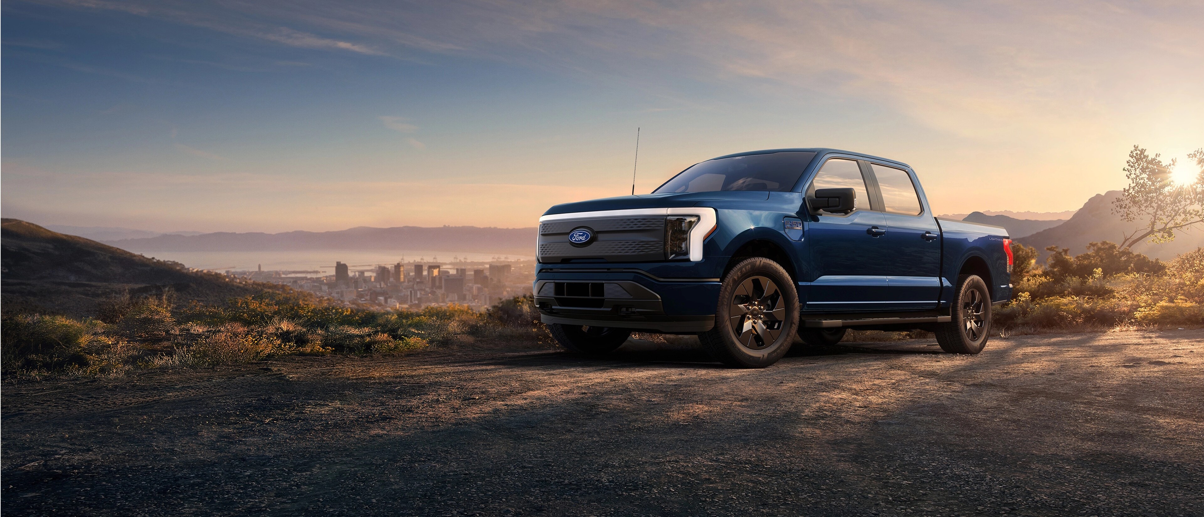 A 2025 Ford F-150® Lightning® pickup parked on a hilltop overlooking the Long Beach, California skyline