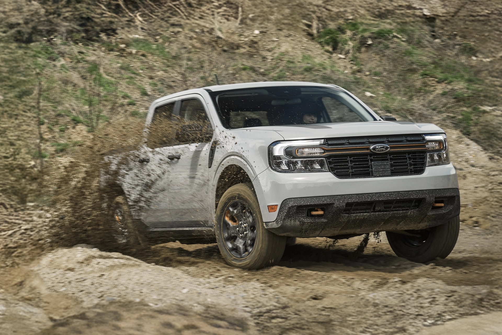 A 2024 Ford Maverick® in Oxford White is being driven off-road up a rocky hill