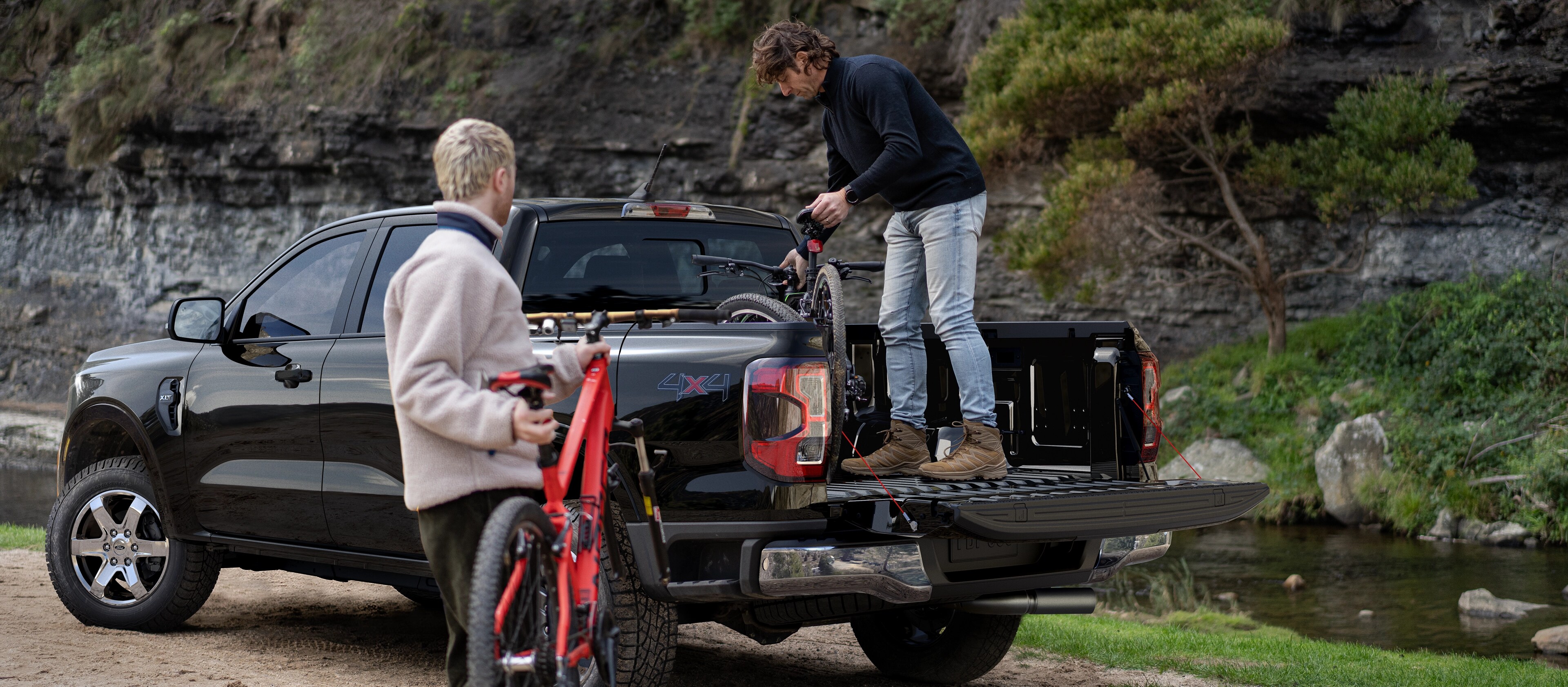 Two people loading gear into the bed of a 2025 Ford Ranger® pickup in Bronze Metallic