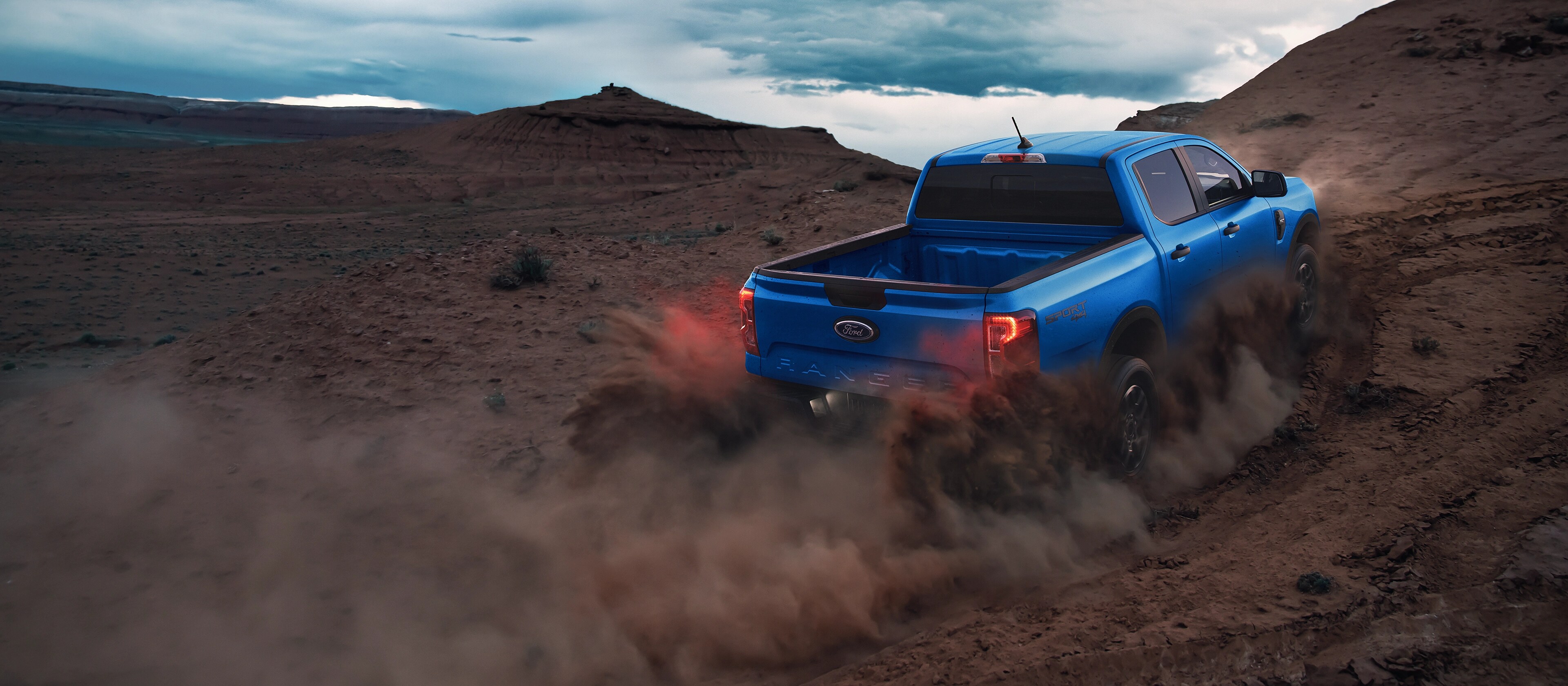 Rear view of a 2025 Ford Ranger® pickup being driven off kicking up dust