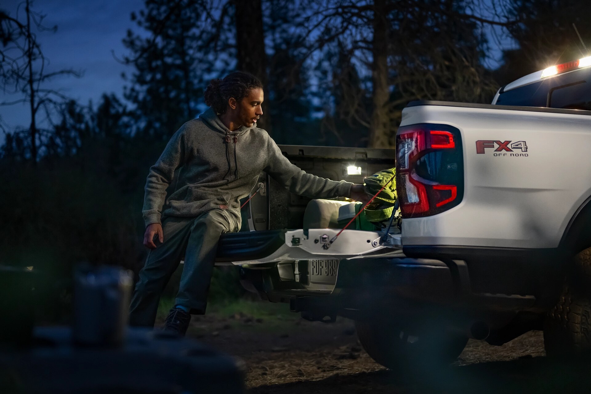 Exterior night shot showcasing bed lighting as person unloads gear from a 2025 Ford Ranger®
